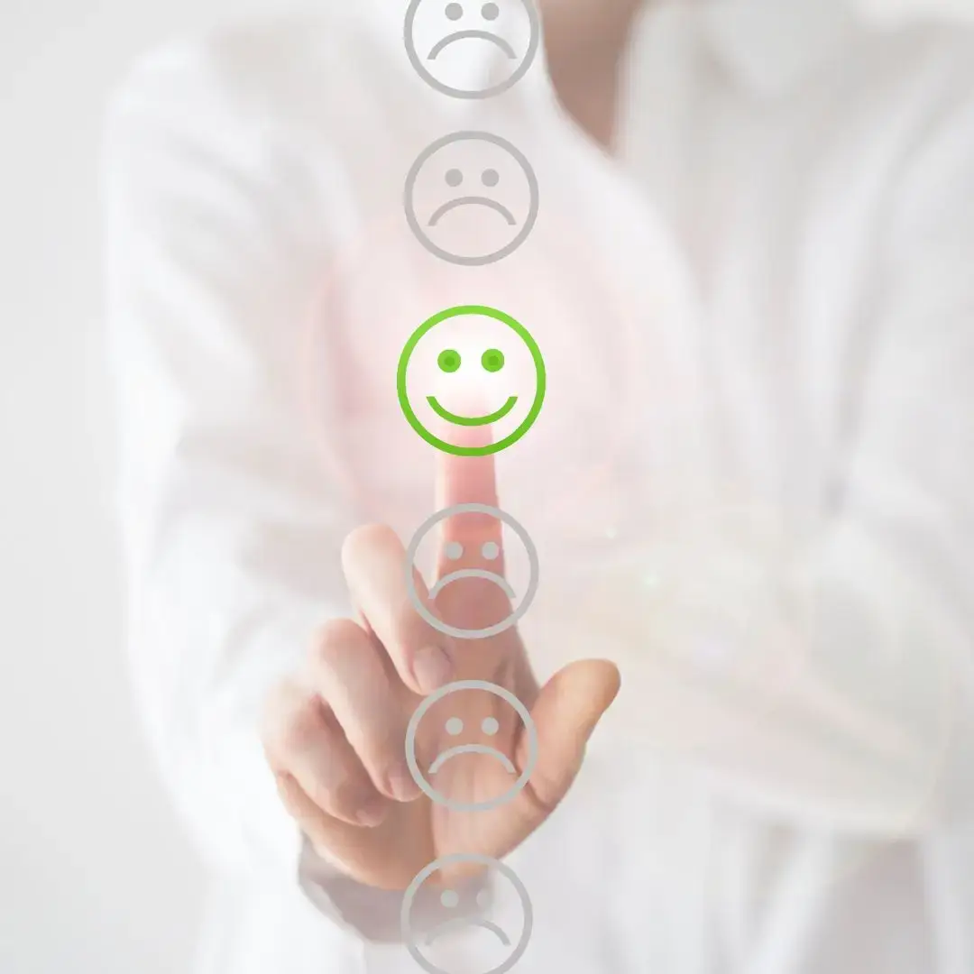 Hand selecting a green smiley face from a feedback scale, symbolising positive workplace culture and emotional wellbeing.