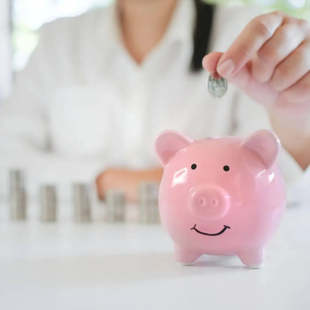 Pink piggy bank on a desk, representing financial health and personal wellbeing.
