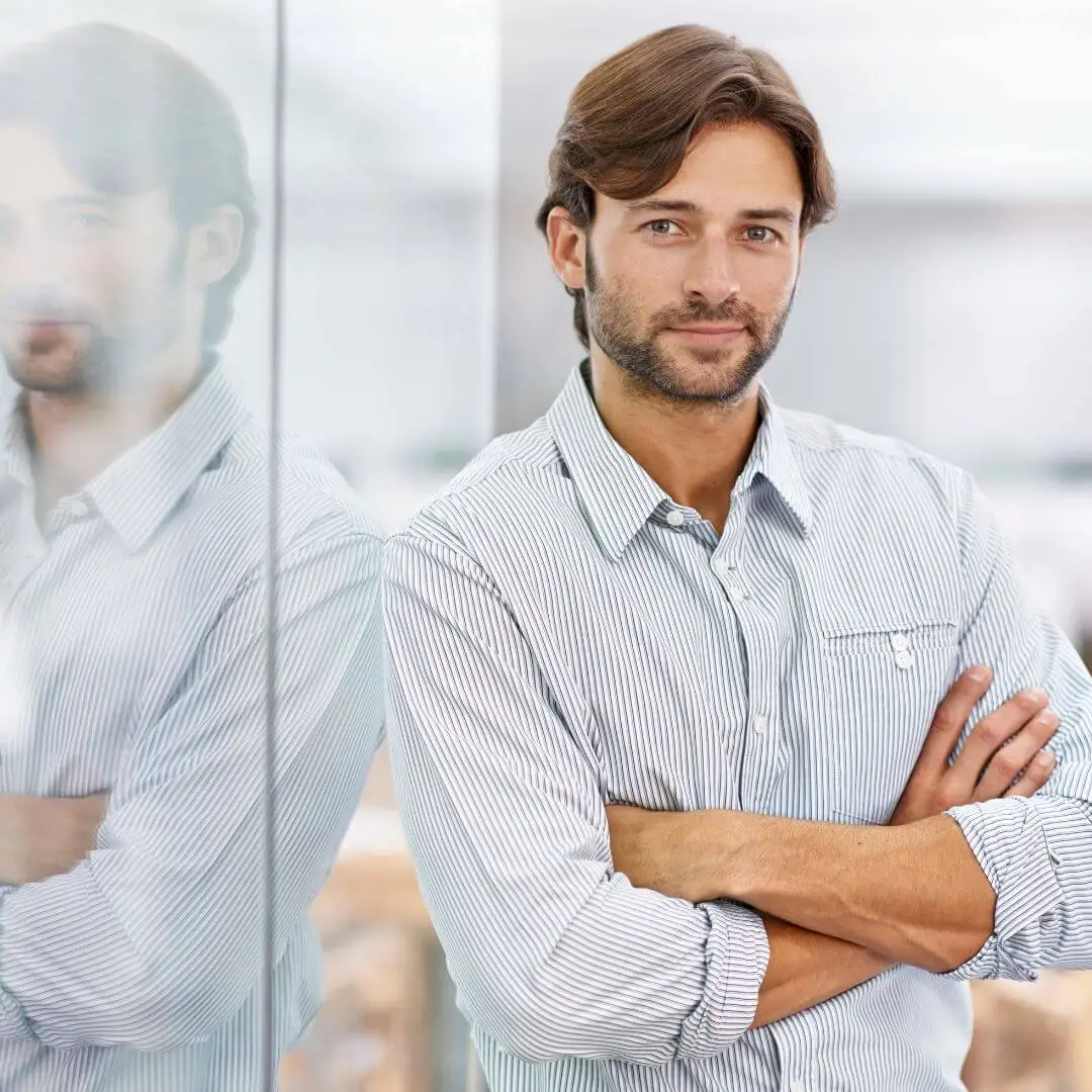 Calm, confident man standing with arms crossed, symbolising self-leadership and mental fitness through Positive Intelligence.