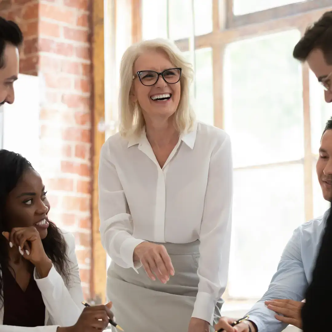 A confident mid-life female facilitator leads an energising team workshop focused on wellbeing, leadership, and collaboration.