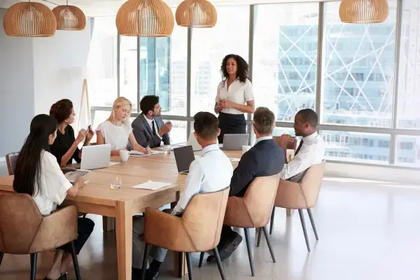 Diverse team applauding a colleague during a boardroom meeting, representing inclusion and collaboration.