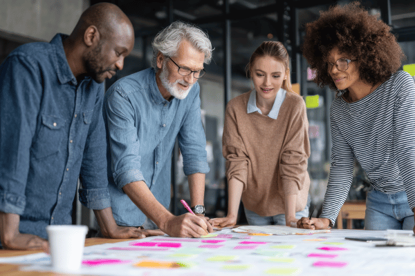 Diverse team collaborating and problem-solving, symbolising co-design of sustainable workplace wellbeing solutions.